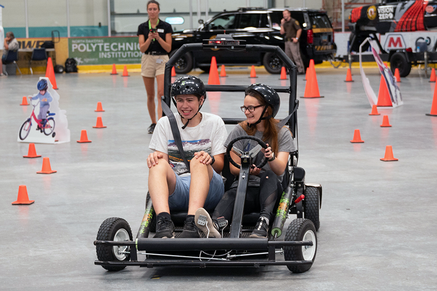 Two children riding a go-kart and learning driving skills.