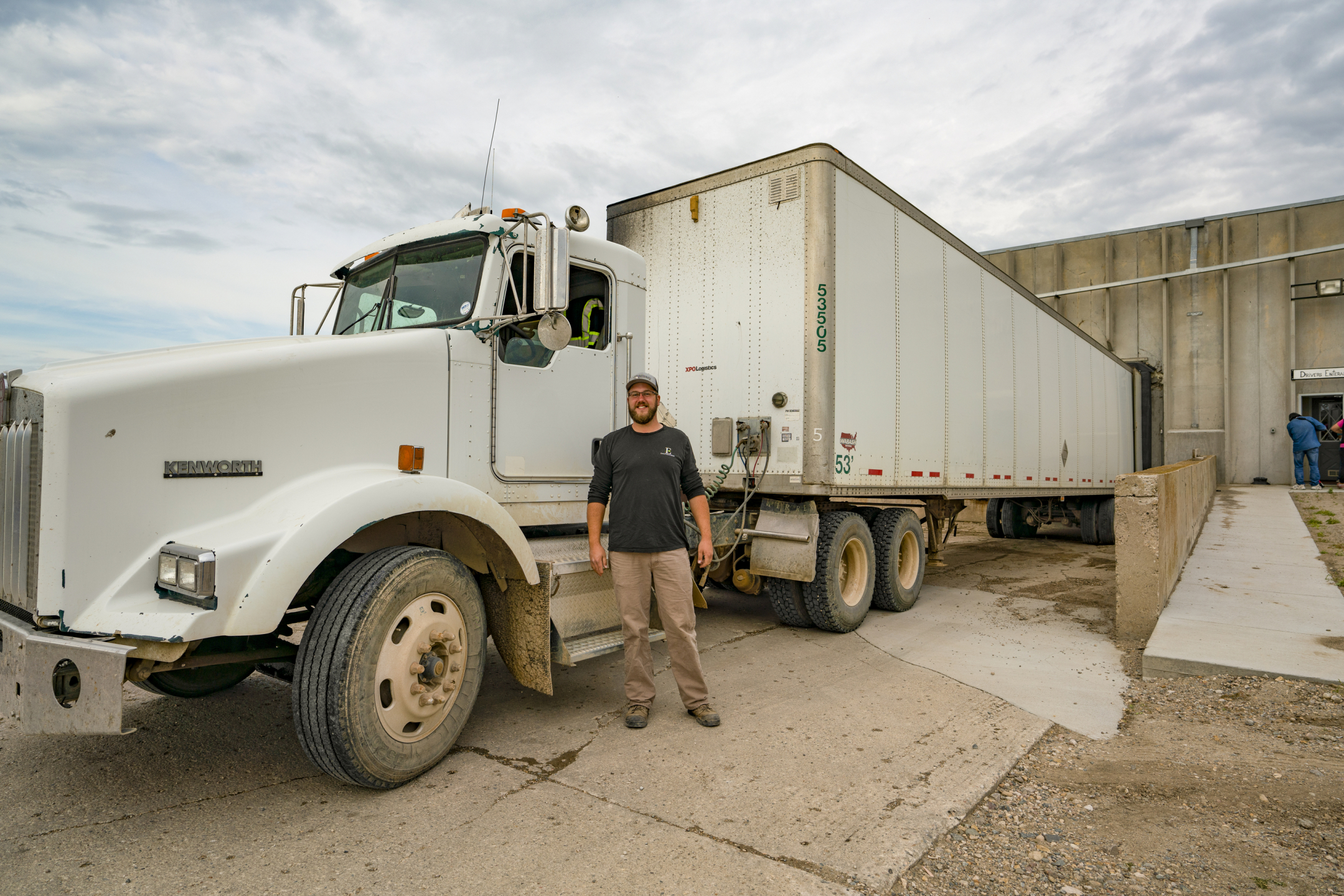 Commercial truck driver smiling and standing in front of a truck