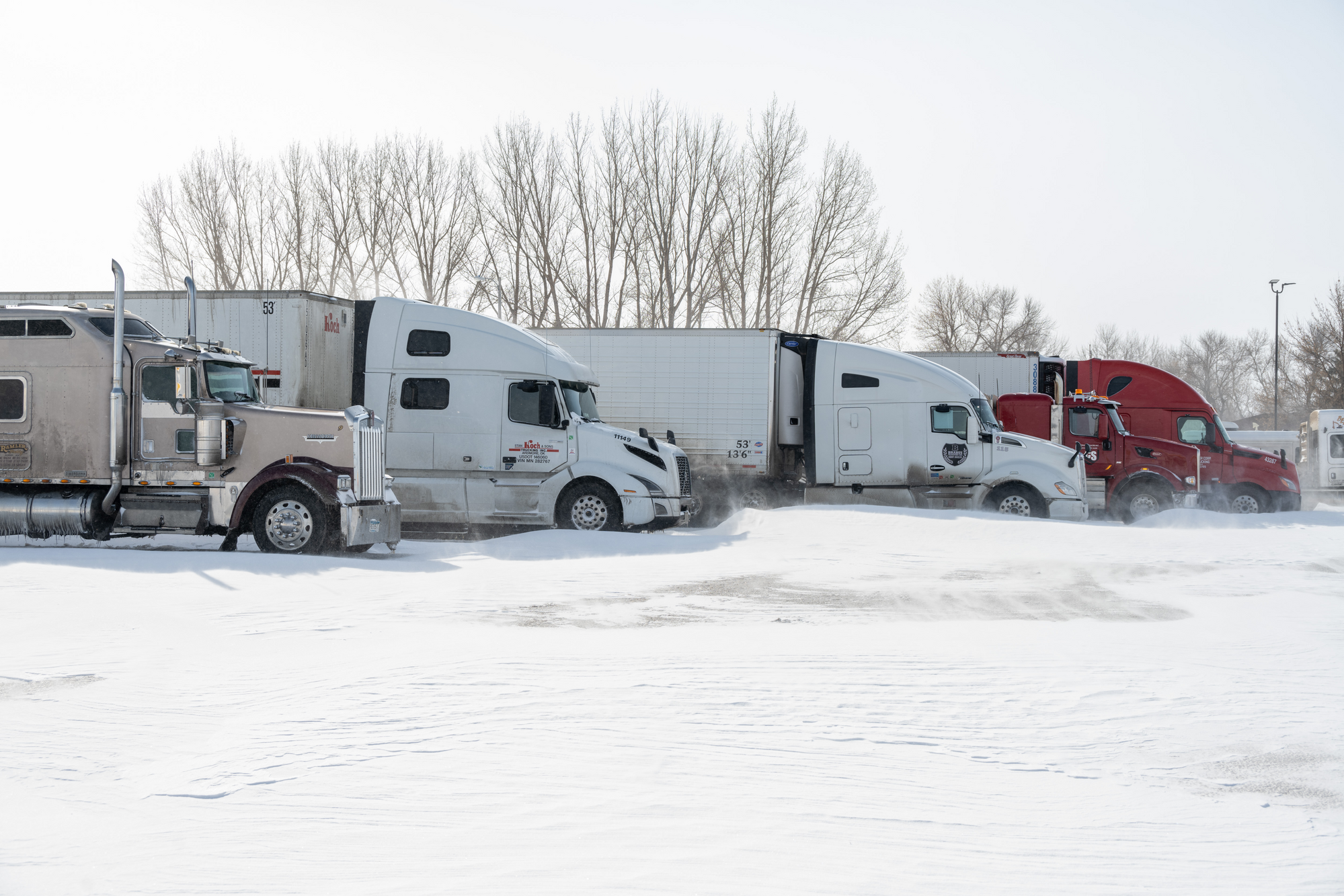 Semi trucks parked next to each other on a wintery day.
