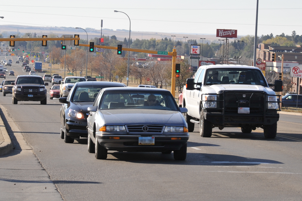 Various noncommercial vehicles driving on a busy North Dakota street.