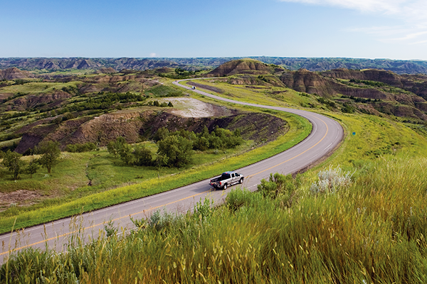 Pickup driving down highway in Theodore Roosevelt National Park