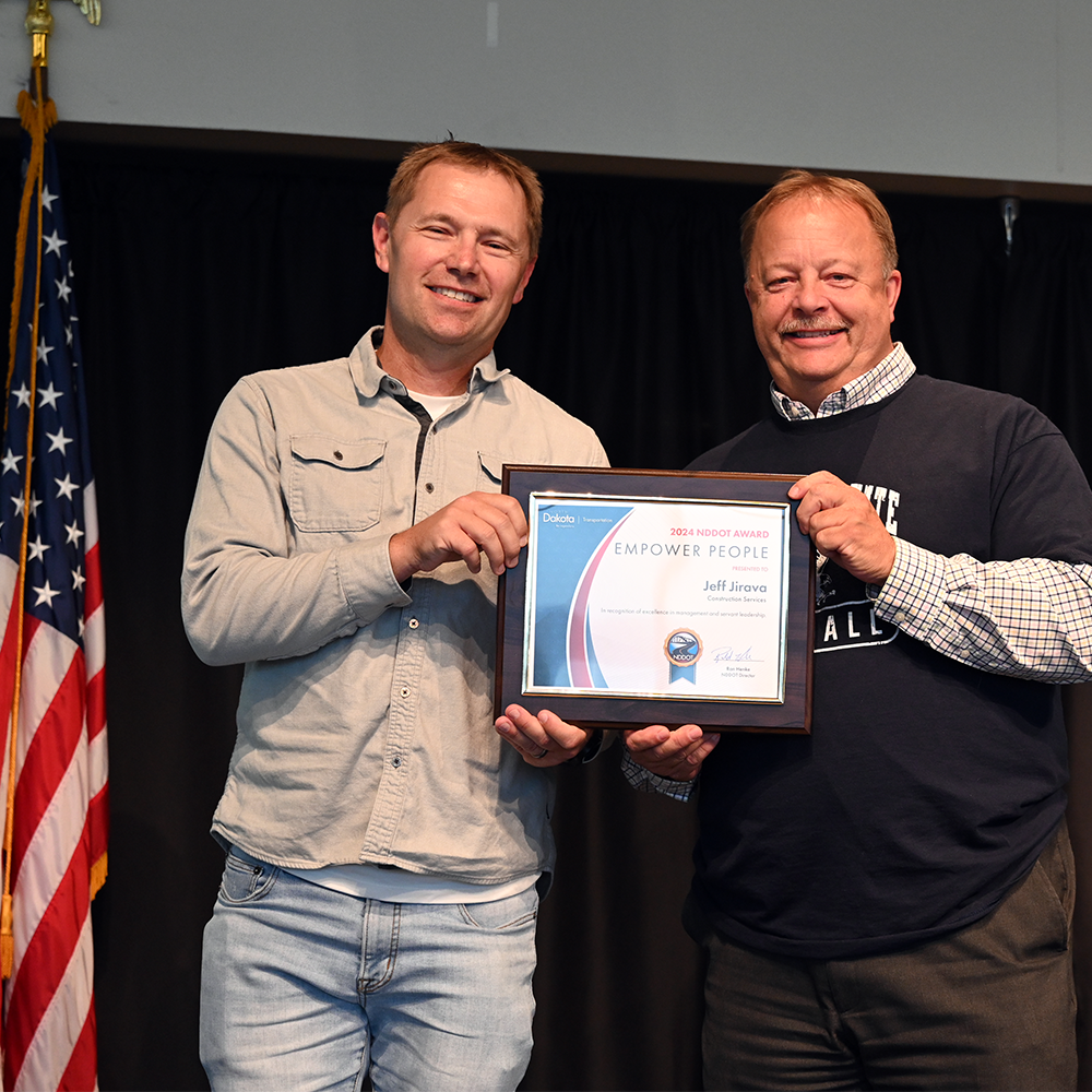 Two men hold an award