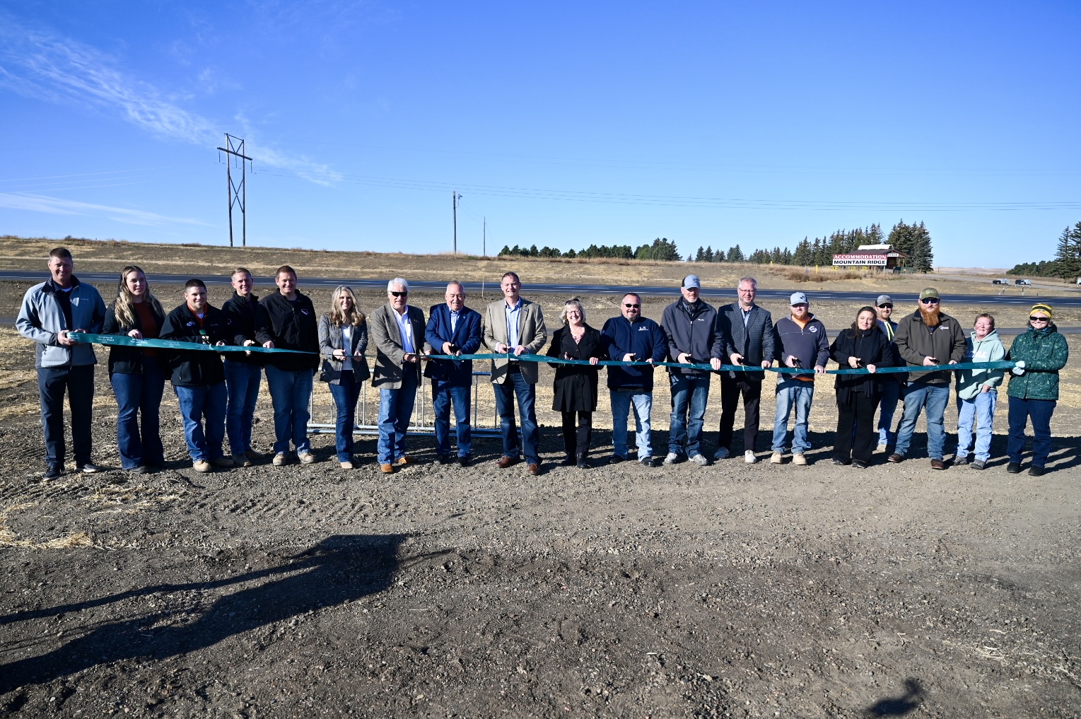 19 people prepare to cut the ribbon at US Highway 85