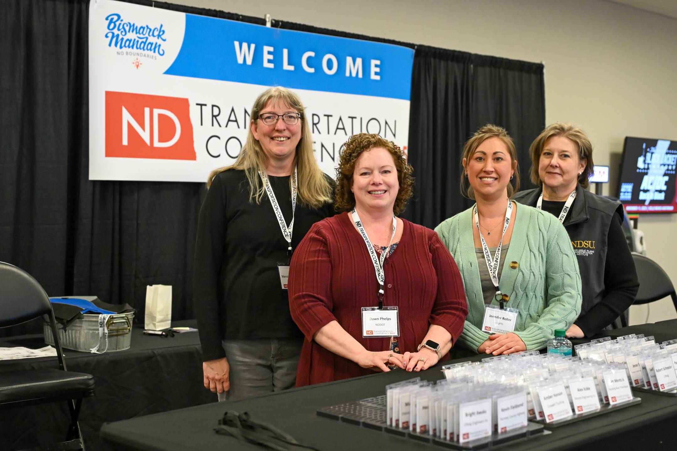 Manda Van Dorsten, Dawn Phelps of the NDDOT, Jennifer Roller, Tracy Wing of Upper Great Plains Transportation Institute stand behind the registration desk at the 2025 North Dakota Transportation Conference.