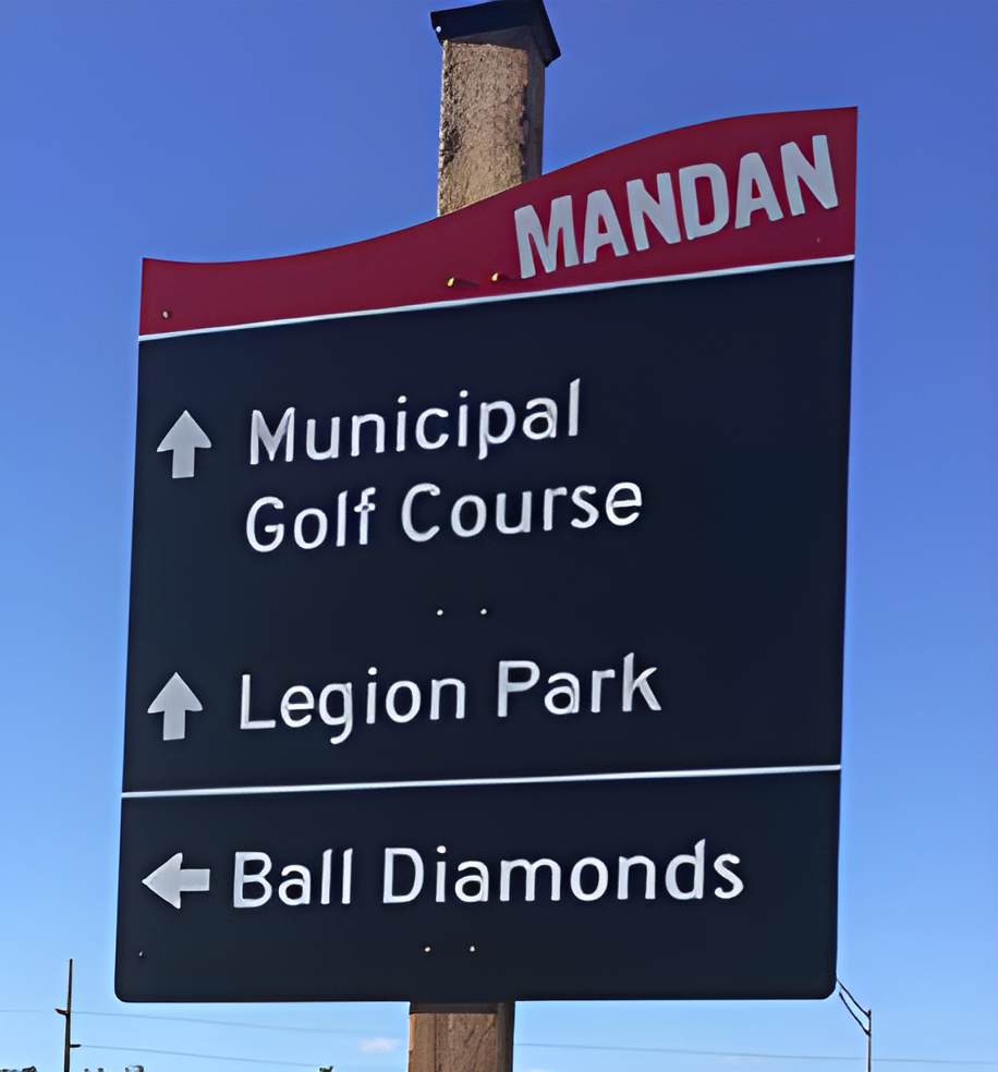 Signage giving directions to a golf course, park, and baseball field.