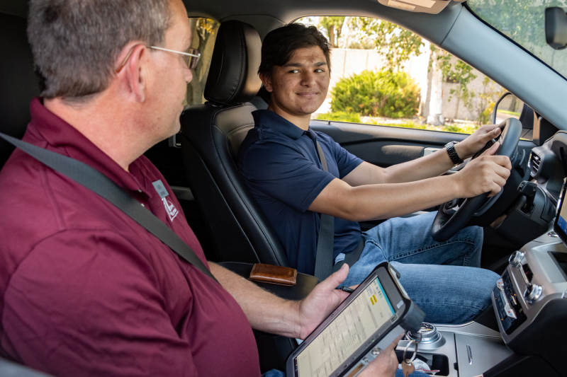 Teen driver seated with an NDDOT employee taking his driver license test.