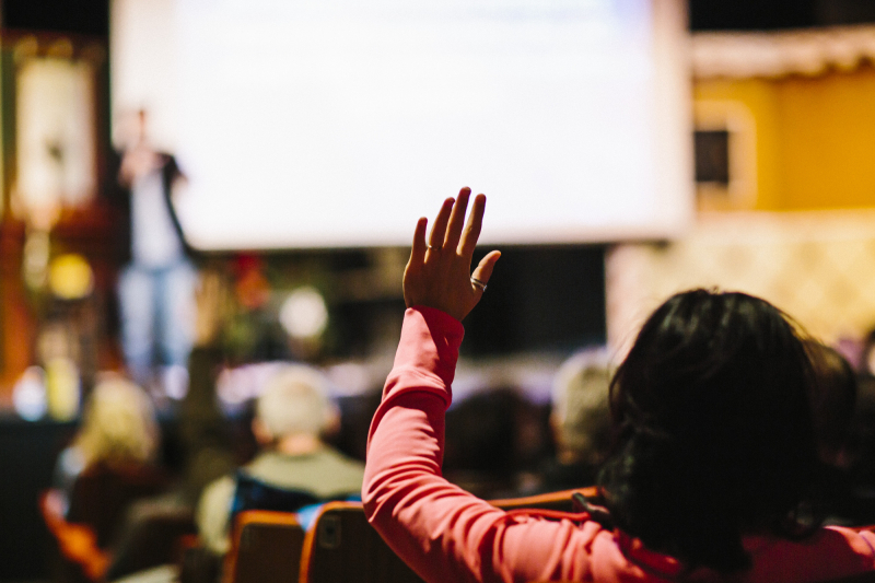 a person raises their hand at a public presentation