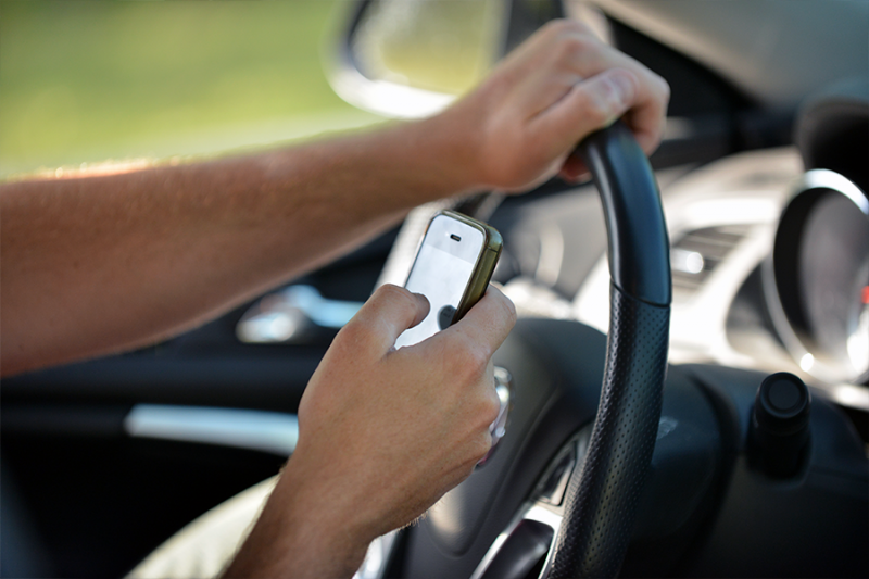 Hands using cell phone while driving.